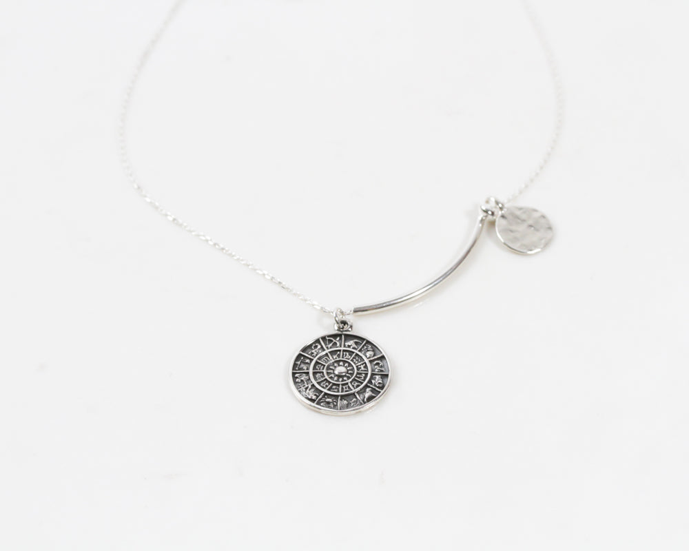 A brilliant zodiac sterling silver coin and textured disc hang spaced apart by a smooth tube bead and a rondelle bead. All elements delicately hang from our barely their sterling silver chain. Handmade in the USA.