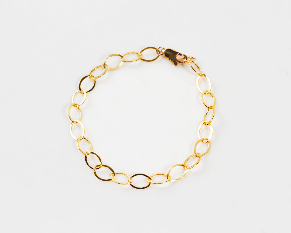 Image shows close up our our 14 karat gold oval link bracelet. It glints and gleams and catches the light beautifully. A lobster clasp closer will keep the bracelet securely on you. Each oval is linked together. Great layered or stand alone.