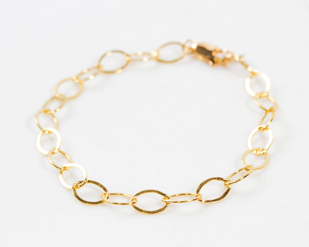Image shows close up our our 14 karat gold oval link bracelet. It glints and gleams and catches the light beautifully. A lobster clasp closer will keep the bracelet securely on you. Each oval is linked together. Great layered or stand alone.