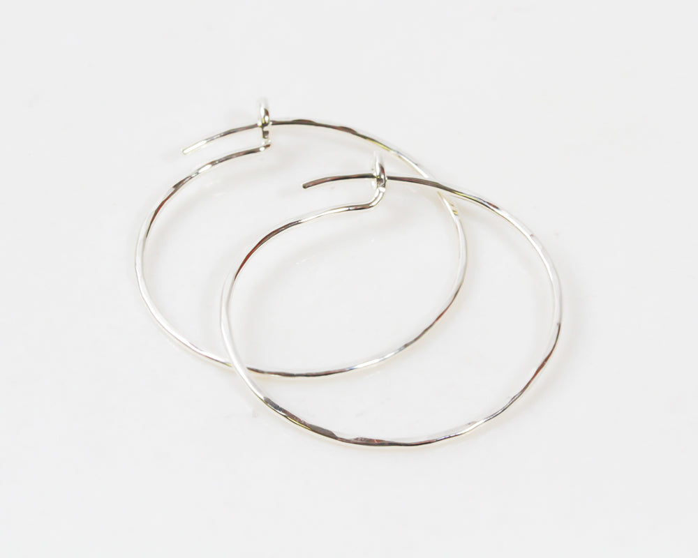 Image shows close up of our 2 inch sterling silver hoops earrings. Handcrafted and handmade by our team of artisans, each earring is unique with a wonderful hand hammer texture that gives it an organic and unique look. They are light and wearable.