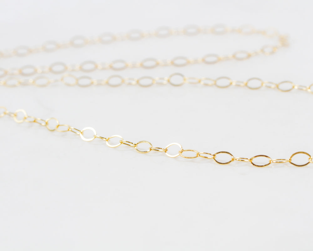 Image shows close up of our exquisite 14 karat Gold Filled Oval Link Chain Necklace. Create a super chic look for all occasions and ensembles. Each 8X6 oval link glints and gleams. Wear it long or short and make a statement. Great layering necklace